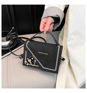 Macro shot of black handbag with white herringbone stitching and gold buckle