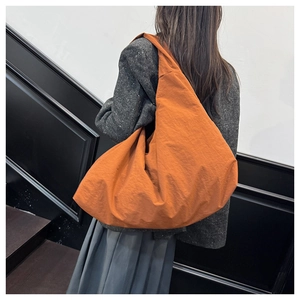 Detailansicht einer orangefarbenen Nylon-Schultertasche mit breitem Trageriemen und Platz