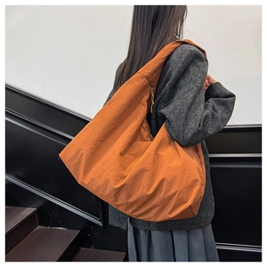 Detail der orangefarbenen Nylon-Tragetasche mit Faltenstruktur und Halbmondform