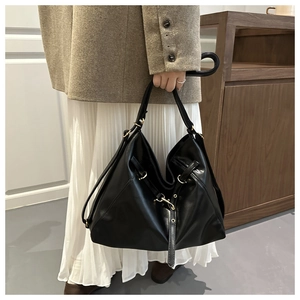 Detail view of glossy black leather tote bag with gold hardware and adjustable strap