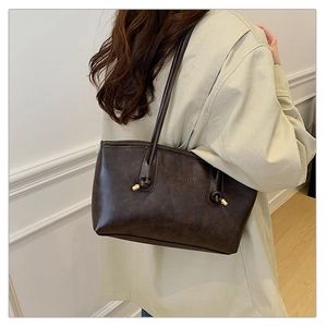Model wearing a dark brown oversized tote bag with minimalist FASHION & BAGS logo embossing