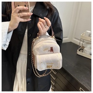 Detail of a beige mini backpack with cat print, gold chain, and secure metal clasp