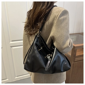 Detail of glossy black tote bag featuring elegant golden buckles and smooth PU leather