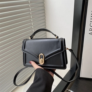 Minimalist black tote bag with gold oval twist lock and adjustable crossbody strap