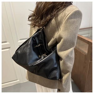 Model wearing a large black vintage tote bag with gold hardware and a pleated texture
