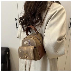 Mini brown canvas and leather backpack featuring cat print and chain strap on a model