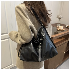Detail of black glossy PU leather tote bag showing soft texture and metal buckle on strap