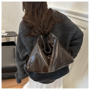 Detailed back view of a large chocolate brown leather hobo bag worn by a model