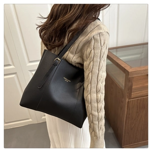 Detail of black leather tote bag with adjustable gold buckle strap and fashion logo