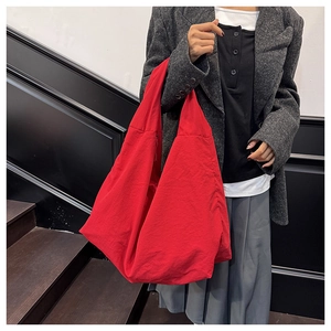 Detailansicht der großen roten Tragetasche aus Nylon kombiniert mit einem grauen Blazer