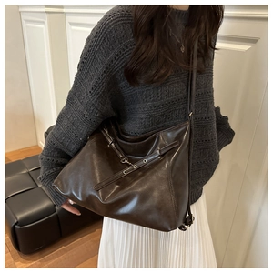 Detail view of large dark brown leather tote bag with silver chain and shoulder strap