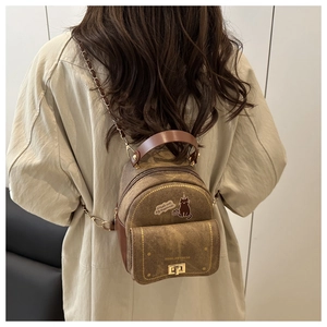 Brown mini backpack featuring a simple cat illustration and gold chain straps shown on a model