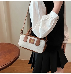 Detail of canvas bowling bag with leather strap worn crossbody by a model in a room