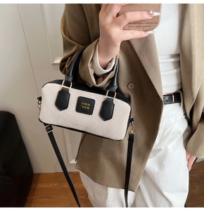 Detail of a retro color-block Boston bag featuring canvas texture and leather handles