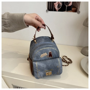 Detailed view of mini denim backpack with cat print, leather trim and gold chain handle