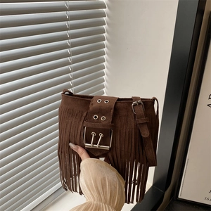 Sac seau marron en daim avec franges et boucle vintage sous la lumière du jour
