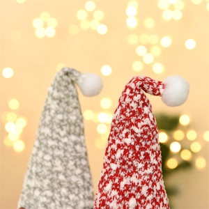 Nahaufnahme von rot und grau gestrickten Weihnachtsmann-Mützen mit weichen Plüschkugeln