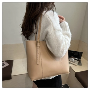 Detail of beige leather tote bag featuring gold buckle adjustable strap and sleek stitching