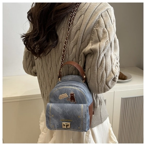 Close-up of a mini denim backpack with leather straps and cute cat patch detail
