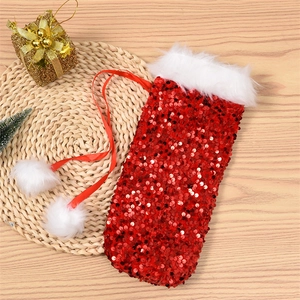 Detail of red sequined Christmas wine bottle bag with plush trim and pompom drawstrings