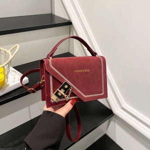 Burgundy contrast flap handbag with white stitching and metal lock on stairs background