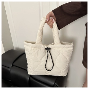 Detail of cream quilted tote bag with heart patterns and functional drawstring closure