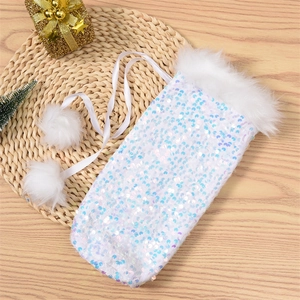 Close-up of white sequined Christmas wine bottle cover with faux fur and pom-pom drawstrings