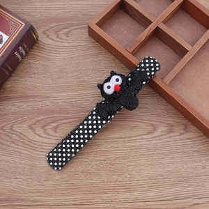 Detail of Halloween slap bracelet with plush bat character on a wooden desk