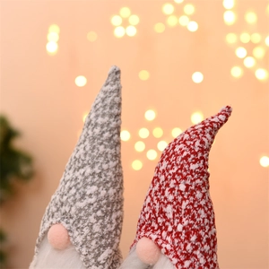 Close-up of two Christmas gnomes with knitted hats and white beards against warm lights