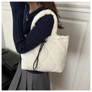 Close-up of white tote bag featuring heart-shaped quilting and woven rope handle detail