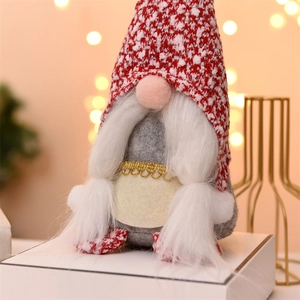 Close-up of a Christmas gnome decoration with red knit hat and warm bokeh light background