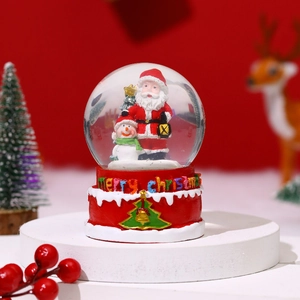 Detail of Christmas snow globe featuring Santa and snowman on a red festive base