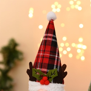 Dettaglio del cappello di Natale a scacchi rossi e neri con pompon e corna di renna