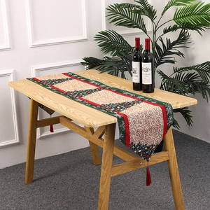 Christmas table runner with knitted holiday tree patterns and red tassel details