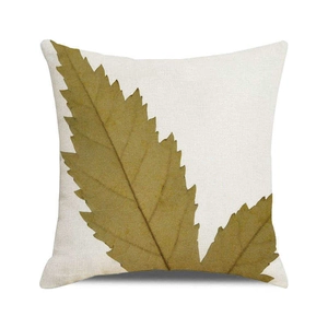 Détail d'une housse de coussin carrée avec une grande feuille d'automne sur tissu crème