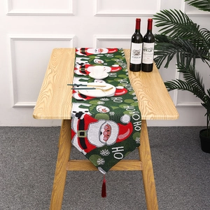 Detailed close-up of knitted Christmas table runner with Santa patterns and red tassels