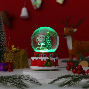 Detail of Christmas snow globe with glowing Santa Claus scene on festive red base