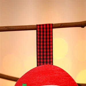 Detail der roten Weihnachtsdeko aus Holz mit Karoband und grünen Stechpalmenblättern