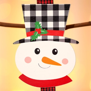 Detail der Schneemann-Holzdeko mit Büffelkaro-Hut und festlicher Stechpalmenverzierung