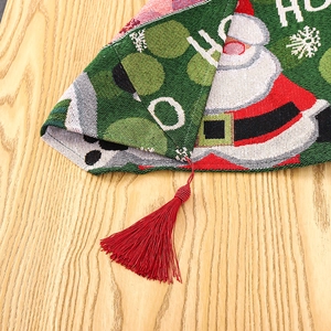Close-up of knitted Christmas table runner with festive Santa patterns and red tassels