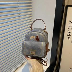 Mini denim backpack with cat illustration and brown leather trim for casual travel use