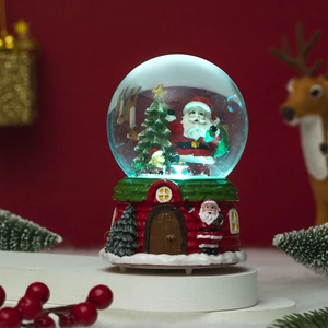 Close-up of a Christmas snow globe with Santa Claus, resin house base, and festive decor