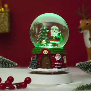 Macro view of glowing Christmas snow globe with Santa Claus and festive red house base