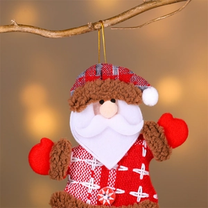 Détail d'une décoration de Noël en tissu Père Noël suspendue à une branche de sapin