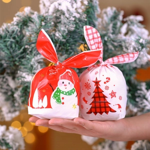 Detail of red snowman and white plaid Christmas tree drawstring gift bags held by hand