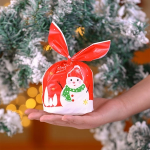 Red Christmas gift bag featuring cute snowman and rabbit ear closure held in hand