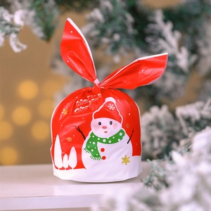Close-up of red Christmas gift bag with bunny ears, snowman print and golden snowflakes