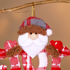 Close-up of Santa fabric ornament with JOY letters on branches for Christmas tree