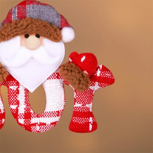 Detailed close-up of handmade fabric Santa ornament with red plaid texture and JOY lettering