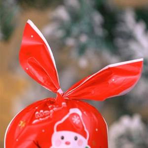 Close-up of red rabbit ear Christmas gift bag with Santa Claus print and snow background